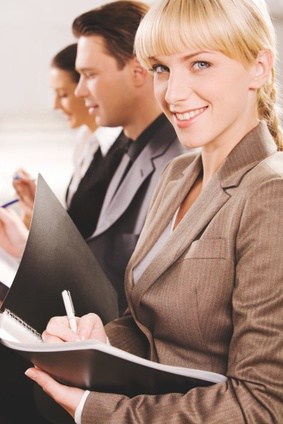 Portrait of pretty woman writing a text and looking at camera at business seminar